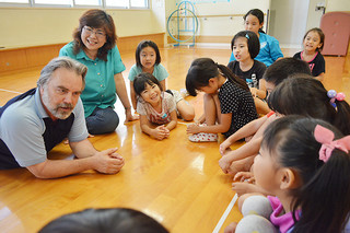 子どもたちに英語の発音を教える野崎旬子、マンリー・スロー夫妻（左側２人）＝17日夕、石垣市子どもセンター