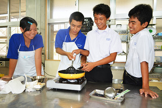 八重山農林高校の体験入学。調理を指導する高校生（中央左）とアドバイスを受ける中学生＝22日午後、同校
