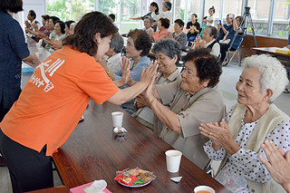 踊りに合わせて、お年寄りとハイタッチを交わす大川パナパナ会の人たち＝27日午前、大川公民館