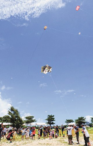 夏至南風（カーチバイ）を受け、空高くあがる凧＝6月30日午後、南ぬ浜町人工ビーチ