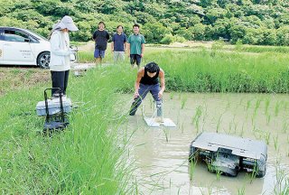 大浜農園の水田で実証実験が行われているアイガモロボ（右）とメタンを分析する装置＝2日午前、美田良地区