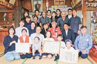 子や孫、ひ孫らに囲まれて100歳を祝ってもらう古堅チヨさん（中央、朱色の着物）＝16日午前、古堅さん宅