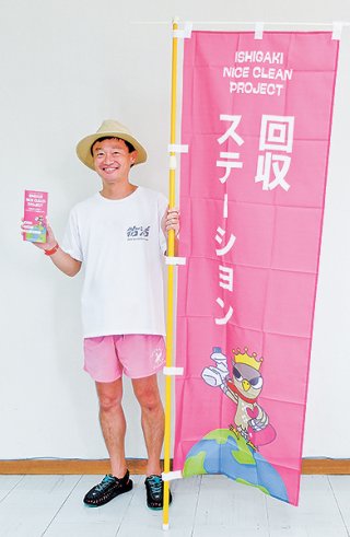 回収ステーションに掲げるのぼりを手にする田中秀典さん＝21日、八重山毎日新聞社