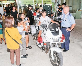 八重山警察署ブースで白バイにまたがる参加者ら＝9月29日、石垣市役所