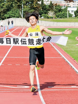 19年ぶりの総合優勝を決めるゴールテープを切る白保の迎里慈詠＝12日午後、市中央運動公園陸上競技場