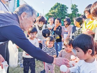 盛岡走友会の十文字会長（左）からの雪玉プレゼントに大喜びの園児ら＝17日夕、おおはまこども園