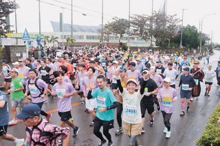 号砲とともにコースへ飛び出していくフルマラソンの出場者ら＝19日午前、石垣市中央運動公園前