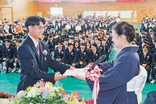 八重山商工高校の卒業式で仲山久美子校長から卒業証書を笑顔で受け取る卒業生ら＝1日午前、同校体育館